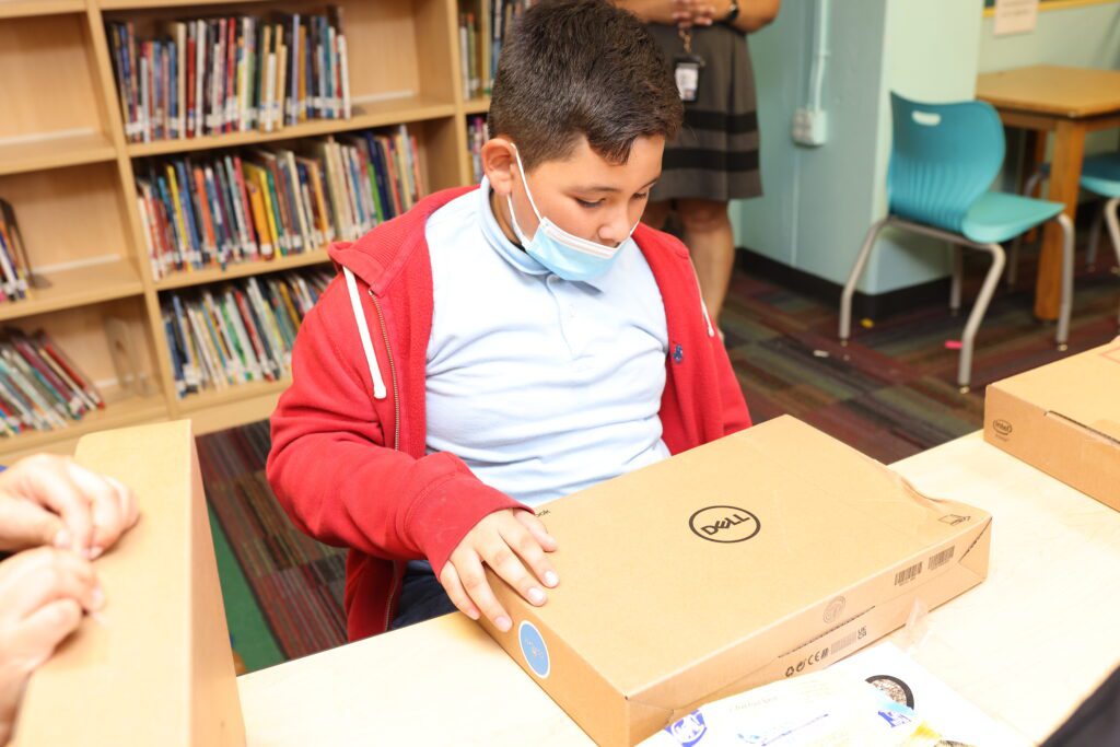 A young student opens a free laptop during an Internet Essentials event.