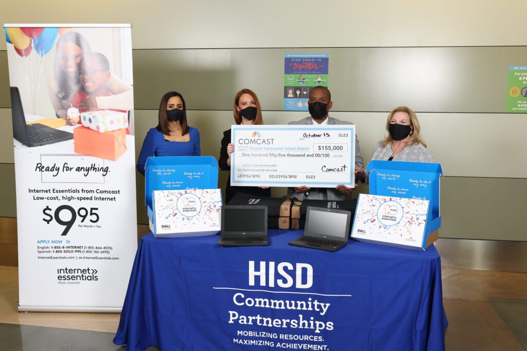 Four HISD Community Partnerships volunteers hold up a giant check behind an Internet Essentials-themed display.