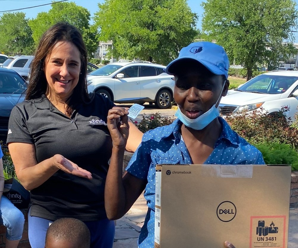 Cheryl Cook holding Dell laptop box while standing with Xfinity volunteer